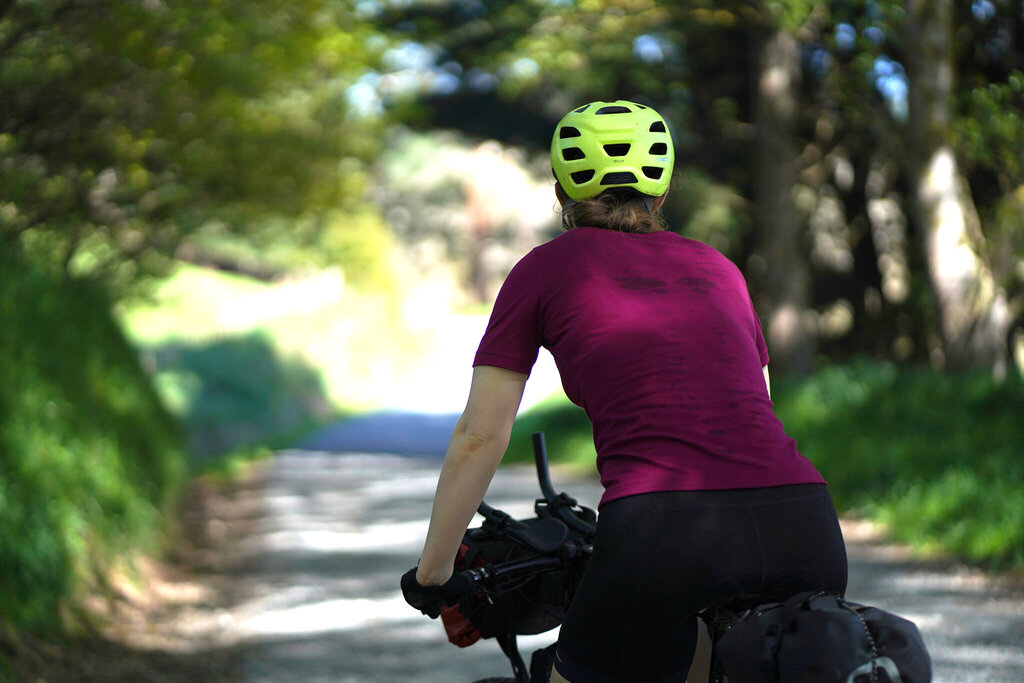 bike helmet safety cyclist bikepacking riding down a forested road in New Zealand